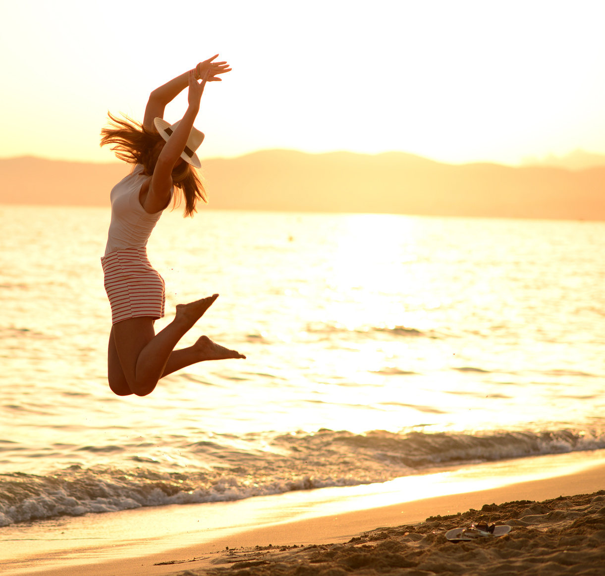 Happy Woman Jumping in Sea Sunset